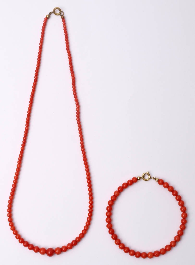 Korallgarnitur: Chokerkette (L.42cm) und Armband (L.19cm). Lachsrote Korallkugeln. Schlösser vergoldet.