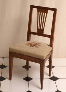 Salonstuhl, 1. Hälfte 19.Jhdt.: Auf vier Spitzfüßen trapezförmige Zarge. Rahmenlehne mit fünffacher Längsversprossung. Sekundärer Bezug mit Petit-Point-Stickerei. Nussbaum. 87x47x40cm.