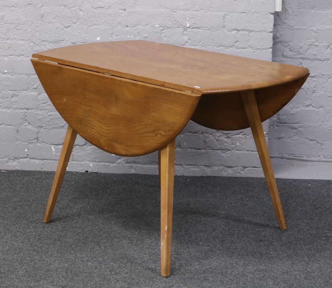 An Ercol drop leaf dining table with splay supports.: An Ercol drop leaf dining table with splay supports.