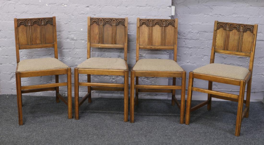 A set of four Ercol oak dining chairs with carved and: A set of four Ercol oak dining chairs with carved and panelled backrest.