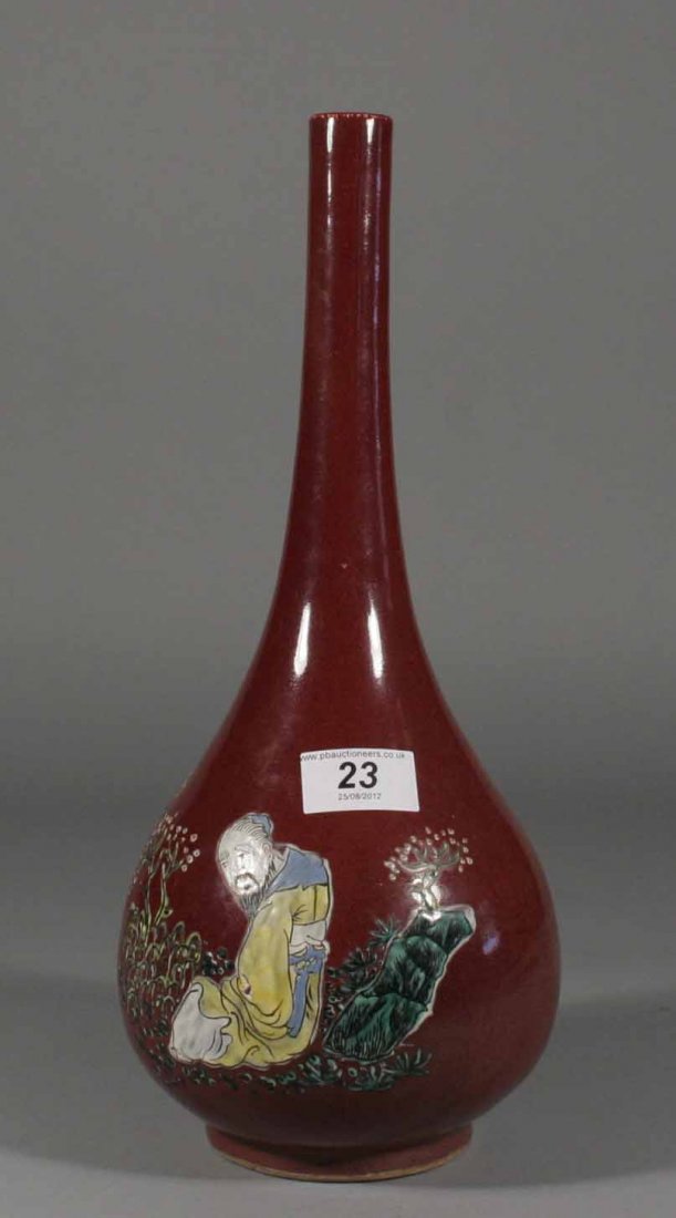 A nineteenth century Chinese bottle vase, decorated: A nineteenth century Chinese bottle vase, decorated with a sang de boeuf glaze and painted with a seated oriental figure amidst foliage, 14''.