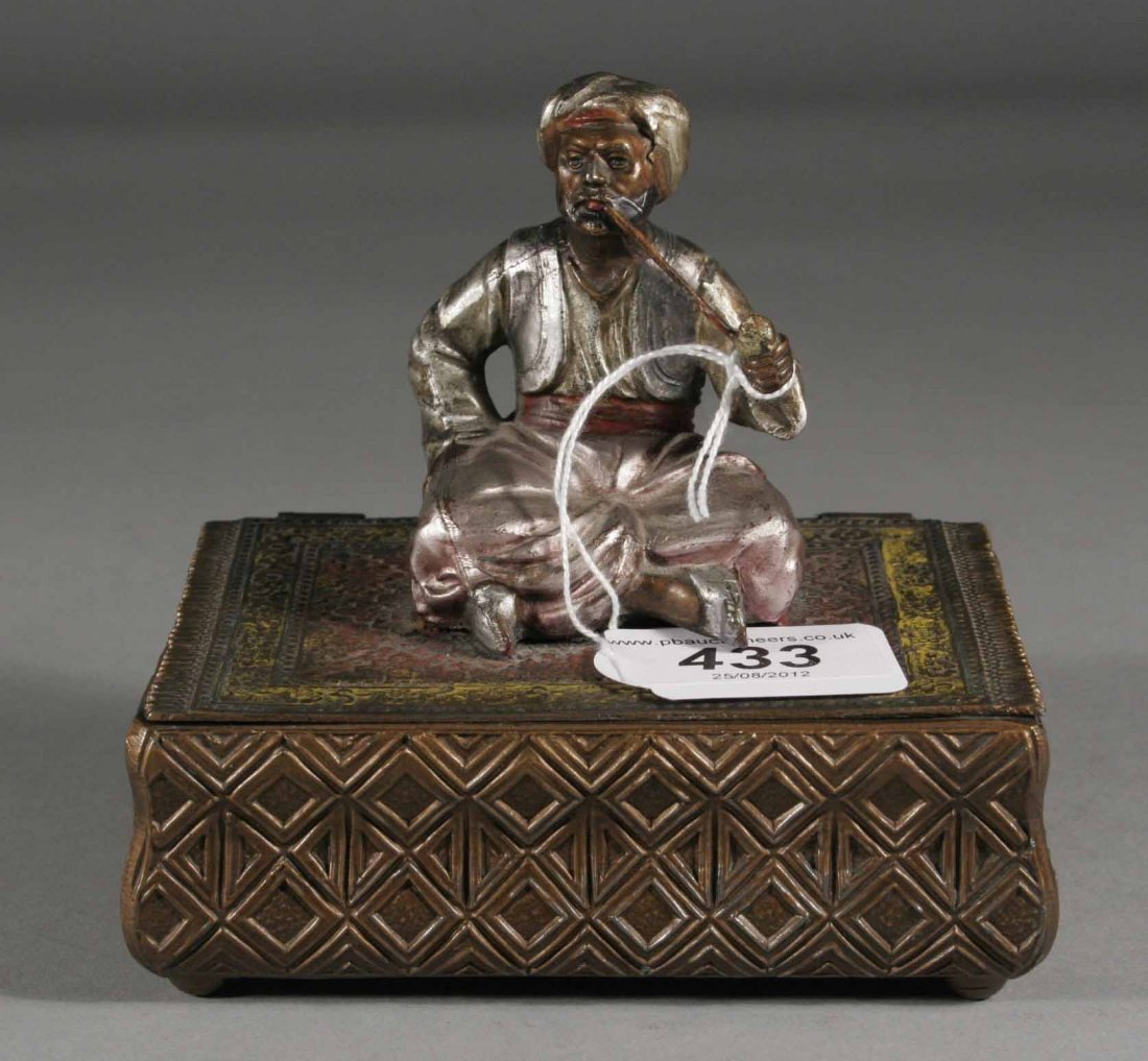 An early twentieth century Austrian cold painted m: An early twentieth century Austrian cold painted metal tobacco box with hinged cover, surmounted by a Turk seated upon a carpet and smoking a pipe, 5.25''.