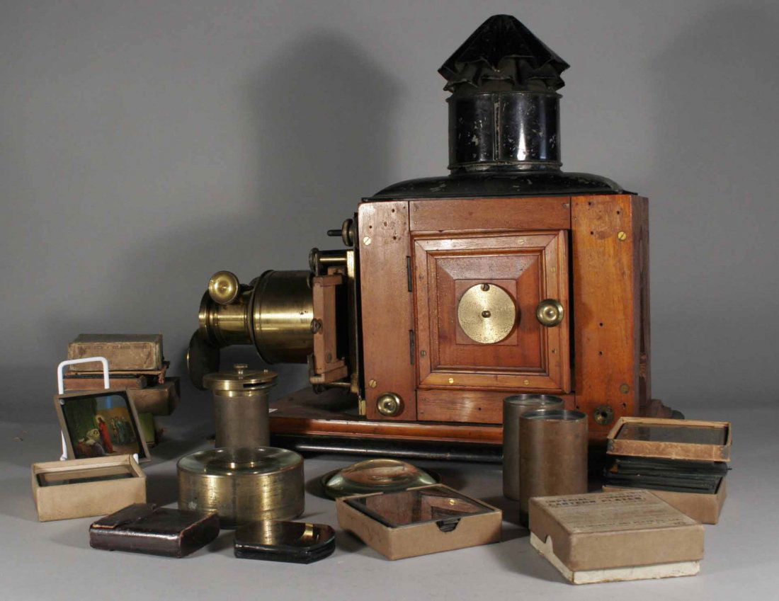 A Victorian mahogany cased magic lantern, along wi: A Victorian mahogany cased magic lantern, along with additional lenses and nine boxes of coloured glass slides, nursery rhymes and religious, 19''.