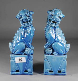 A pair of Chinese turquoise glazed models of dogs o: A pair of Chinese turquoise glazed models of dogs of fo, raised on stylized oblong plinths, 10''.