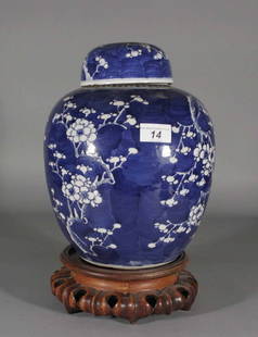 An antique Chinese ginger jar and cover on carved h: An antique Chinese ginger jar and cover on carved hardwood plinth, decorated in underglaze blue with blossoming branches, two concentric rings to the underside.