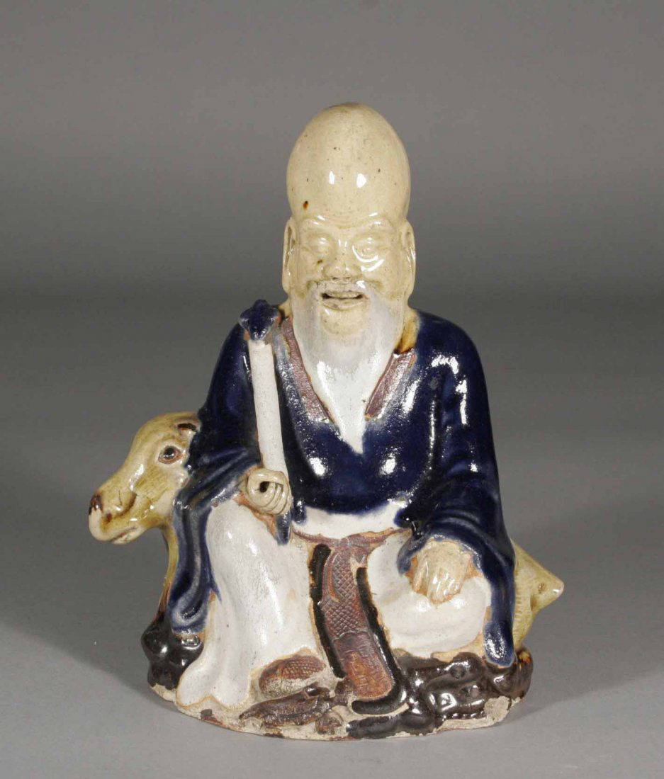 A twentieth century Chinese glazed earthenware figu: A twentieth century Chinese glazed earthenware figure of a sage, seated upon a deer and holding a ruyi sceptre, 7''.