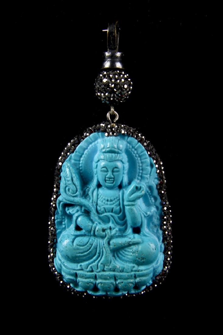 Chinese Turquoise Stone Buddha Pendant: China, Turquoise stone Buddha pendant, seated figure wearing headdress and elaborate robes in a pale blue stone surrounded in a oval shape of smaller stones attached to a chain with a single larger be