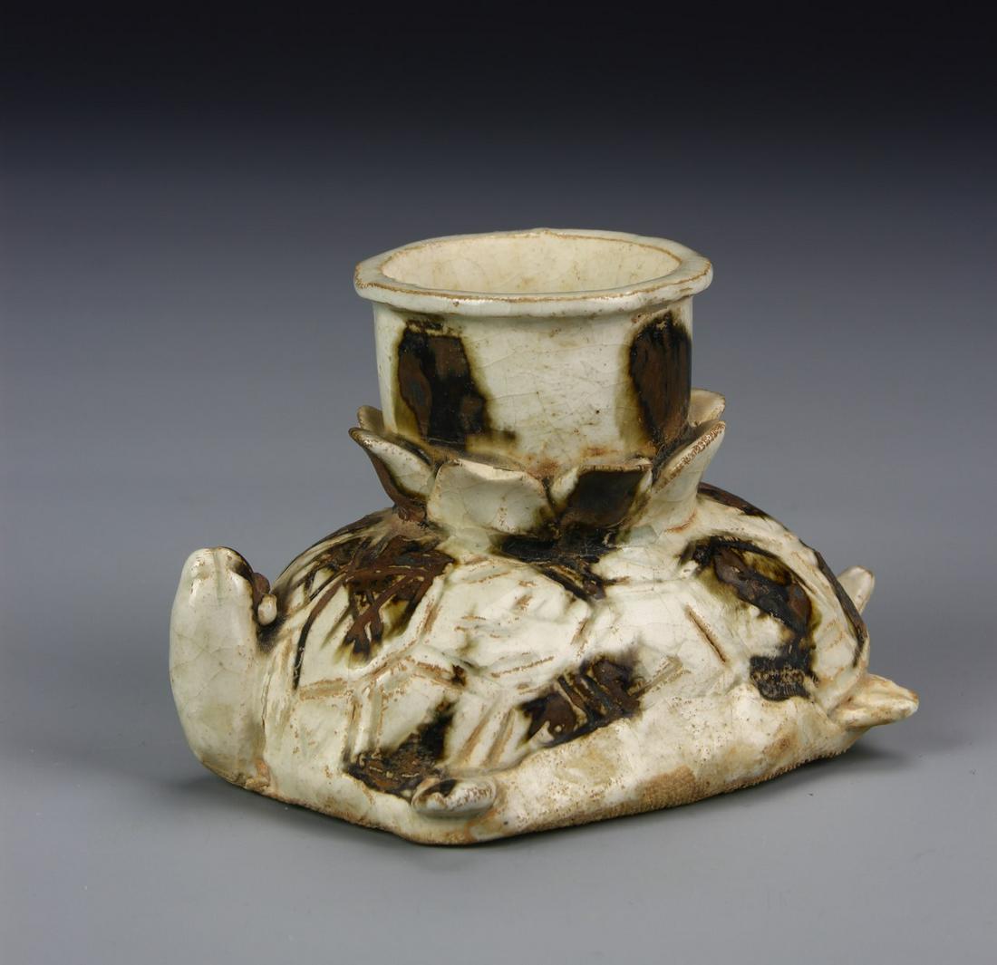Chinese Cizhou Yao Candle Stick: China, Song Dynasty, Cizhou Yao Candle Stick, carved turtle body with flat base, his head poking out and upward with candle stick holder rising from his back, dotted brown shapes against white ground.
