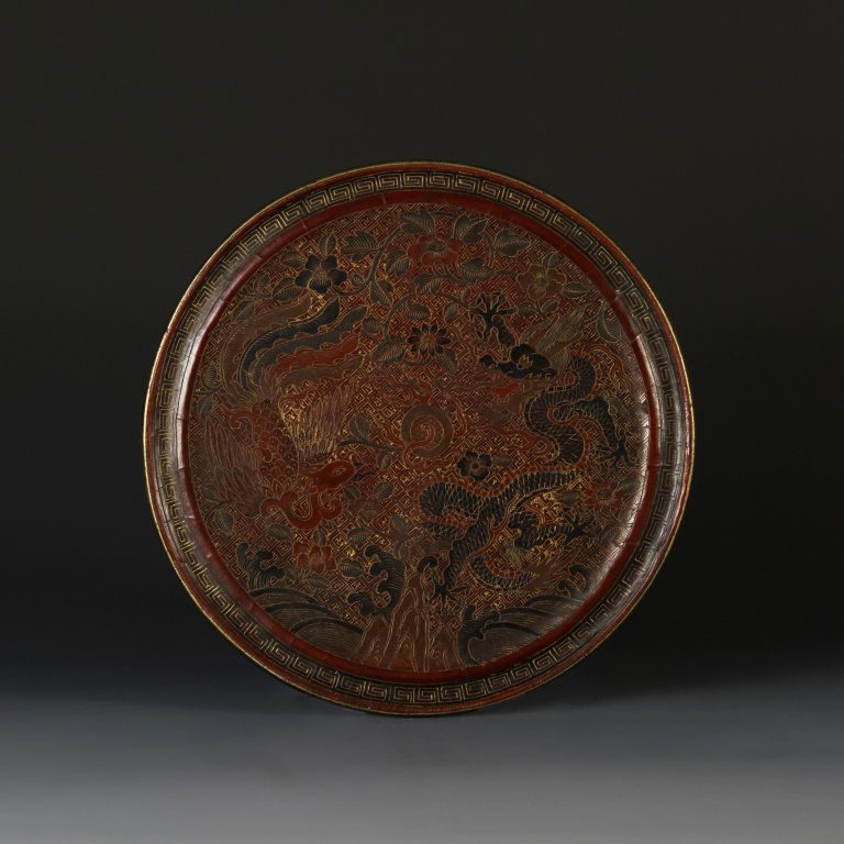 Chinese Bronze Mirror: China, antique bronze mirror, rare design with dragon and phoenix cast in relief chasing a pearl ball amid flowers above mountain and water, encircled with a band of hui motifs, surface formally lacqu