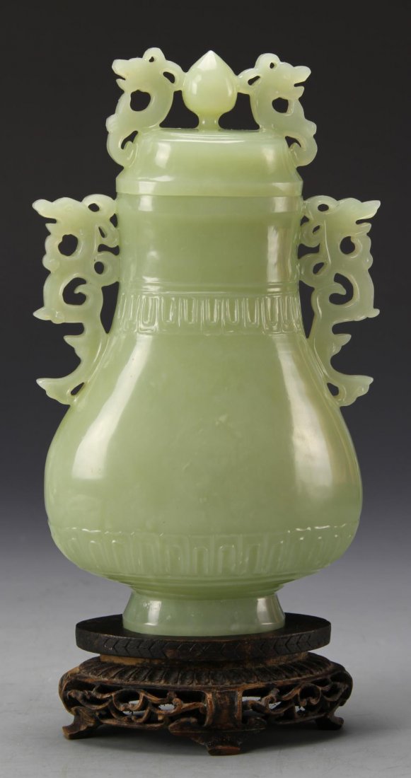 Chinese Jade Vase: China, 20th C., carved jade vase with cover, carved chi dragons ad handles and finials, with carved hardwood stand. Height 6 3/4 in., Width 4 in.