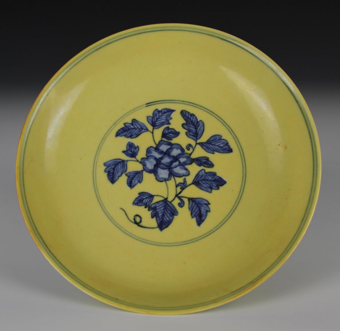 Chinese Yellow-Ground Blue Dish: China, Ming period, the center painted in under glazed blue of a blossoming gardenia leafy spray within a double circle with stylized lotus meander on the exterior, all reserved on a rich lemon yellow
