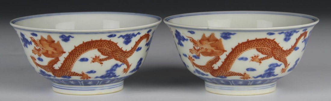 Two Chinese Blue and White Iron Red Dragon Bowls: China, each painted with two striding iron red dragons chasing flaming pearls amid ruyi clouds with a leaping dragon on the interior, Yongzheng mark. Diameter 4 3/4 in.