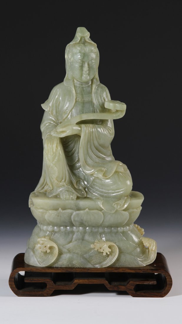 Chinese Carved Jade Guanyin: China, Late 19th C., carved jade Guanyin, holding a ruyi scepter, lotus form base over ocean waves, with rosewood stand. Height 9 1/2 in.