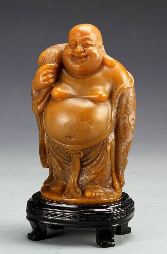 Chinese Soap Stone Buddha: China, soap stone Buddha, traditional smiling image with bald head and bare belly, standing on wooden circular base with four feet. Height 6 3/4 in.