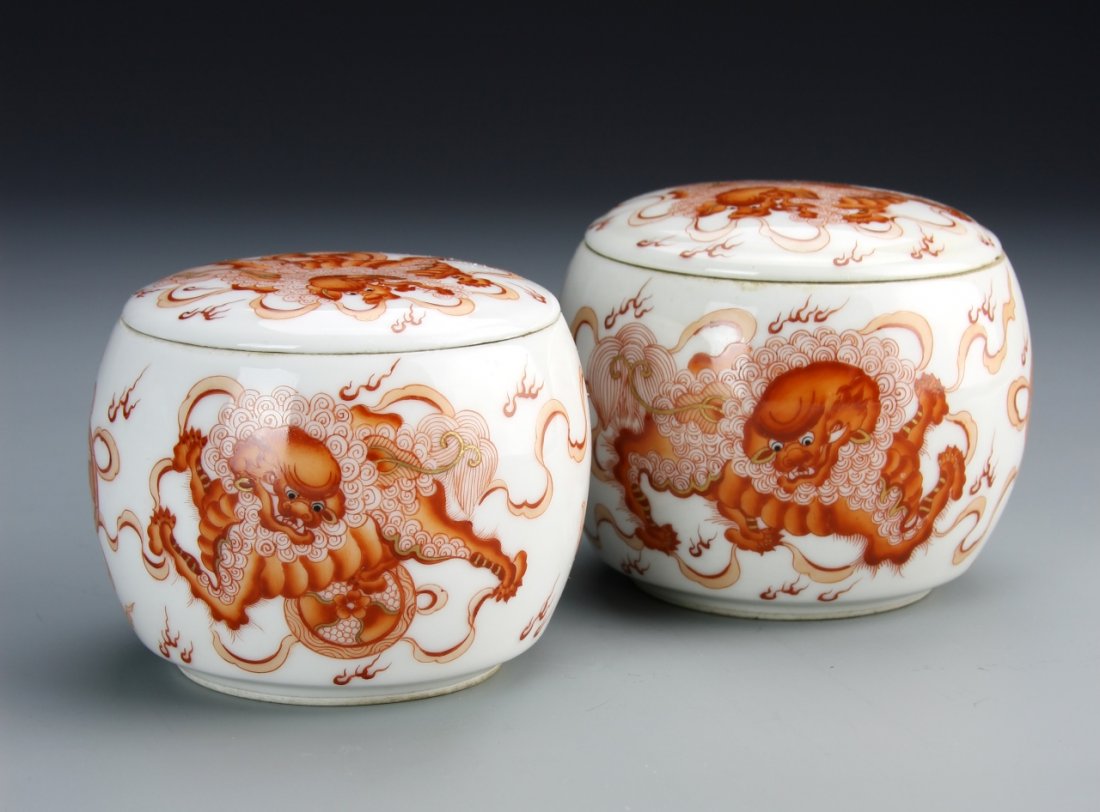 Pair of Chinese Red-Glazed Jars: China, pair of red-glazed jars, with fitted lids, painted with orange foo lions chasing through clouds. Height: 2 3/4 in., Width: 3 in.