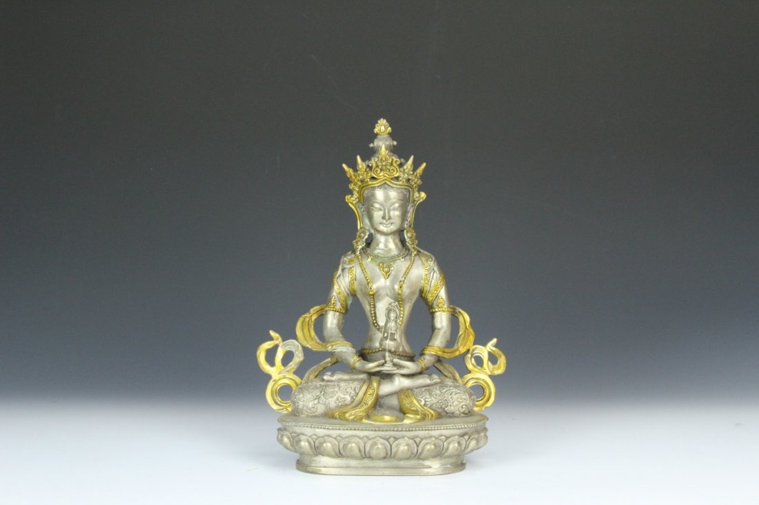 Chinese Metal Buddha: China, metal Buddha in sitting position upon a decorative base with gilded decorative elements. Height 12 in.