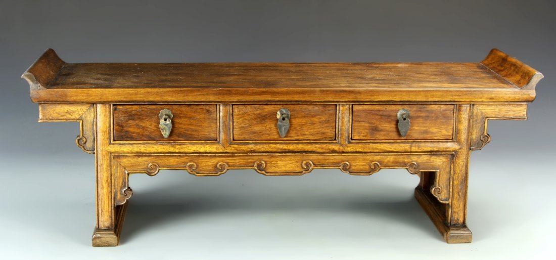 Chinese Huanghuali Mini Altar Table: China, huanghuali miniature altar table with traditional motifs and designs at the apron, with brass pulls. Length 24 in., Width 7 3/4 in., Height 7 3/4 in.
