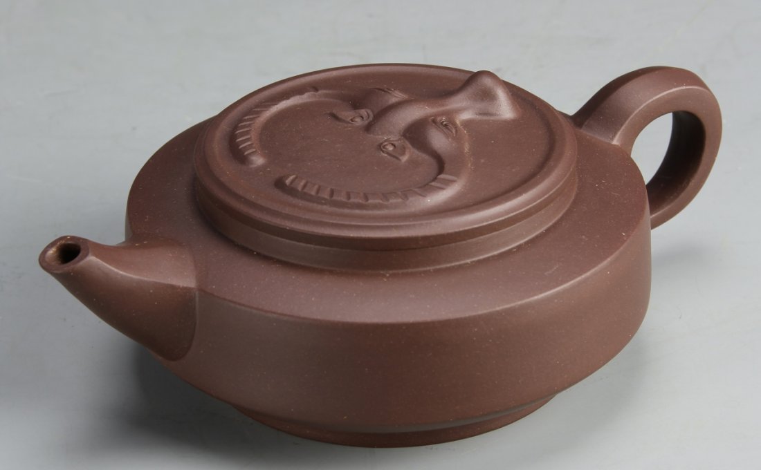Chinese Yixing Teapot, Signed Li Xiao Cheng: China, Yixing teapot, in a rounded form, decorated with an abstractly formed face in relief on the cover, signed Li Xiao Cheng. Height:: 7 1/2 in., Width: 2 1/2 in.