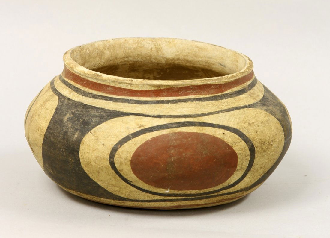 Southwestern Native American Pot: Southwest, Native American, a painted pot in a squat form, with black and red circular designs, on a cream base. Diameter 7 in., Height 3 1/2 in.