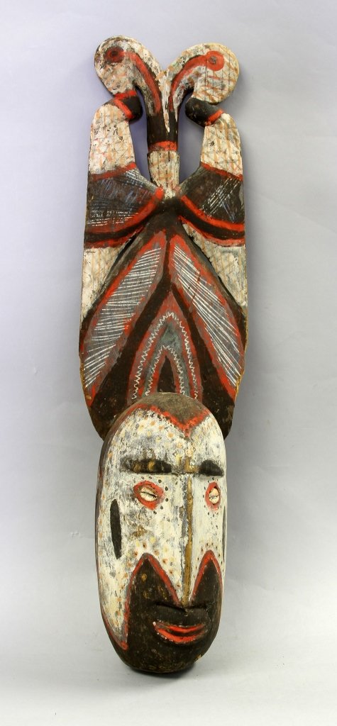 New Guinea Asmat Mask with Stork Headdress: New Guinea, Asmat mask with a stork headdress made from a light wood, brightly pigmented with patterns accenting the headdress, with cowrie shell eyes. Height 24 in. Provenance: From the Dr. Robert Go