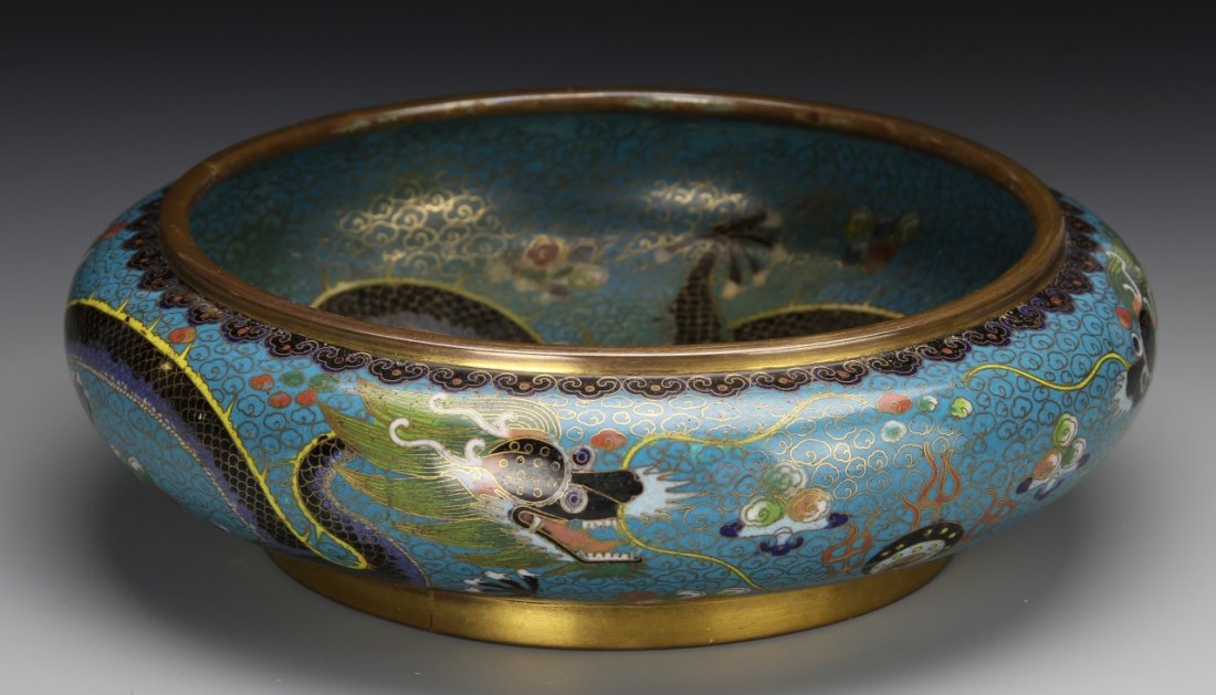 Chinese Cloisonne Brush Washer: China, 19th C., cloisonne brush washer, flattened round shape, gilt edging, dragons curl around the interior and exterior against a blue ground with gold stylized cloud design, contrasting floral pain