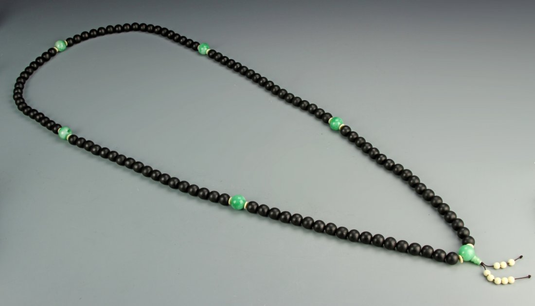 Rare Black Chenxiang Buddhist Prayer Beads: China, black Chenxiang wood Buddhist prayer beads, composed of 108 beads, each 1.6 cm in diameter, spaced with four larger jadeite beads, fitted with huanghuali wood box. Overall Length 68 in. Provena