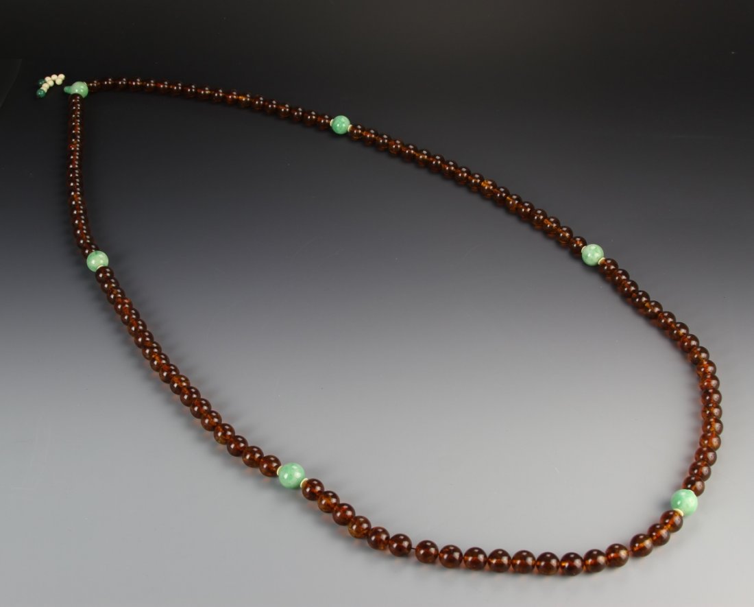 Chinese Amber Buddhist Prayer Beads: China, amber Buddhist prayer beads, comprising 108 golden colored beads each 1.80 cm diameter, spaced with six larger jadeite beads, fitted with huanghuali box. Length 75 in. Provenance: Property of a