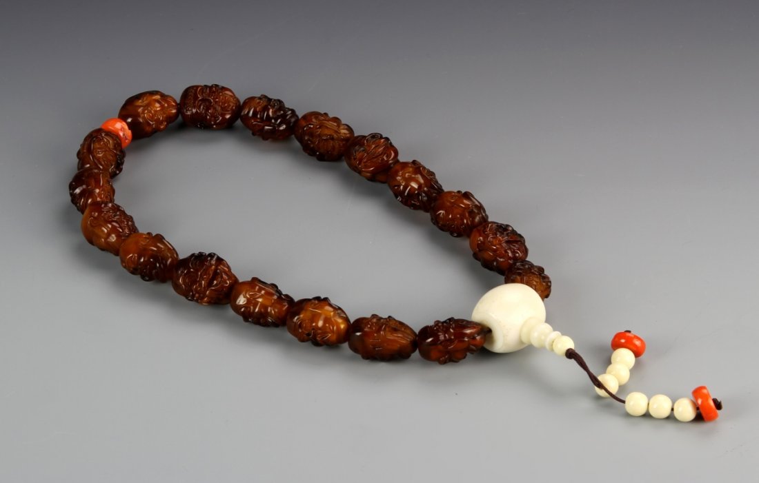 Chinese Carved Amber Luohan Buddhist Prayer Beads: China, Luohan prayer beads, comprising 18 carved Luohan heads with ivory and coral beads. Length 16 in. Provenance: Property of a Portland, Oregon Estate