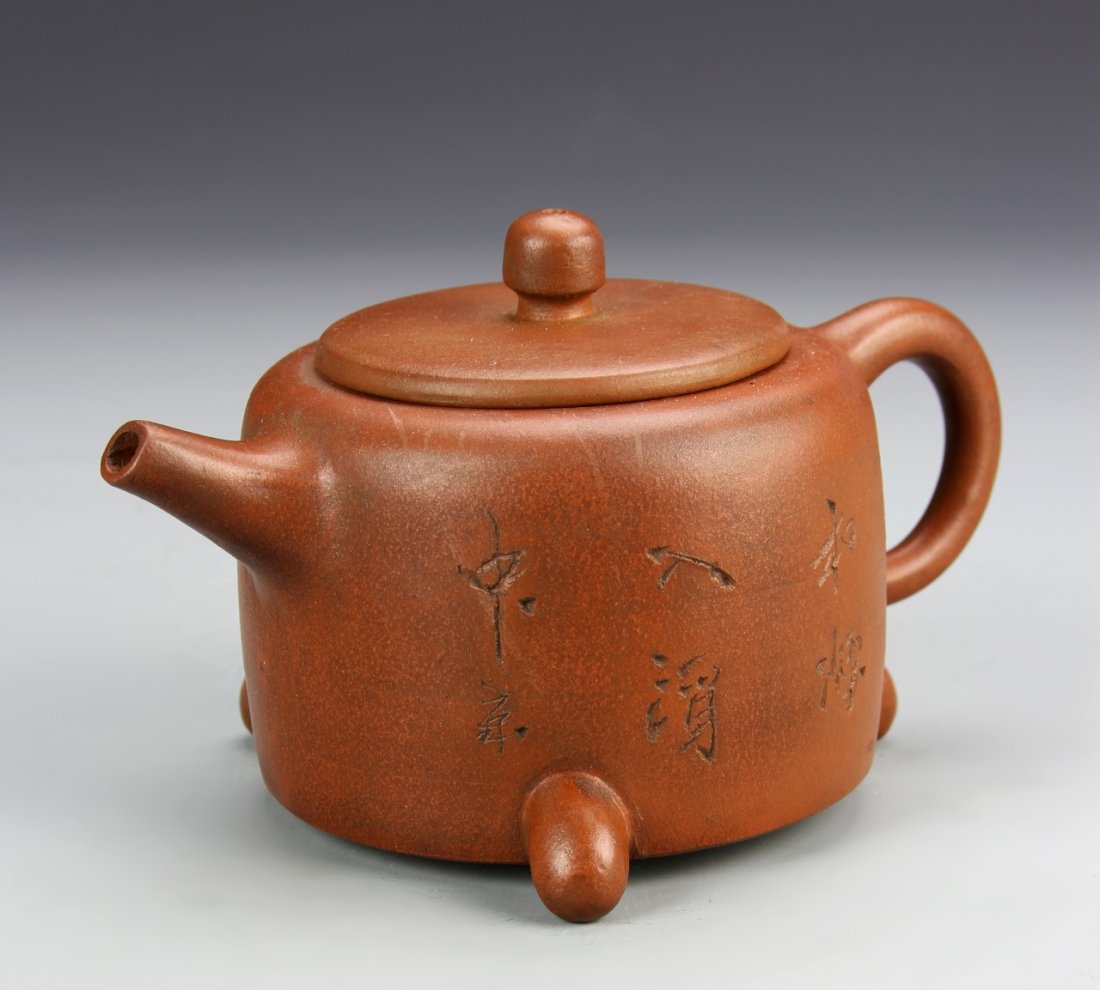 Chinese Yixing Zisha Teapot: China, Yixing Zisha teapot, glazed rust red and panels of calligraphy on both sides of the tea pot with two feet and a mark upon the vase. Width 6 3/4 in., Height 4 1/4 in. $100 - 200