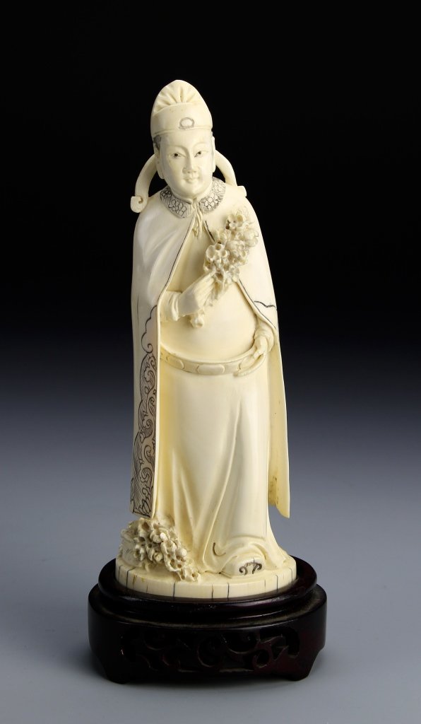 Chinese Ivory Figure: China, 19th C., ivory figure, with elegant robes and headdress showing a scrolling design, holding flowers in his hand, with stand. Height 7 1/2 in. Provenance: From the private collection of Mrs. Pea