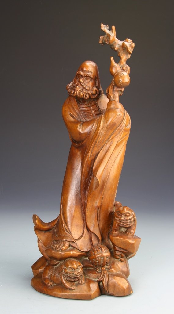 Chinese Boxwood Daimara Figure: China, expertly carved boxwood Daimara figure holding onto a staff with flowing robs and an intricately rendered beard, standing upon a rocky base accompanied by two foo dogs. Height 16 in.