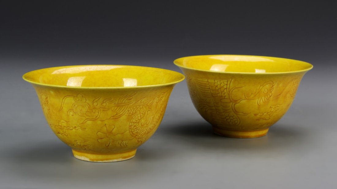 Two Chinese Yellow Glazed Bowls: China, two yellow glazed bowls, with slightly footed bases, decorated with a subtle design of dragons auspicious symbols, with Ming Mark. Height 2 1/2 in.