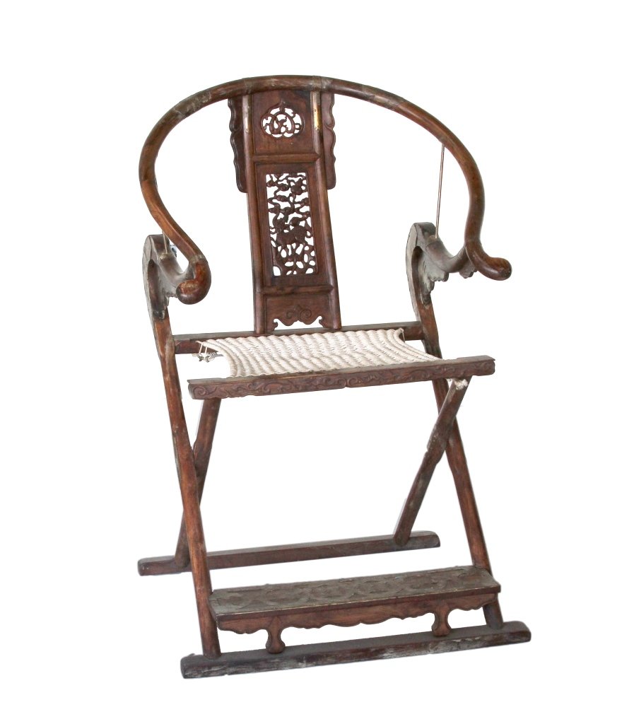 Chinese Huanghuali Folding Chair: China, 19th C., Huanghuali wood folding chair, with a carved horseshoe-shaped back, ornately carved spat with repetitive organic and animal designs, with a rope seat. Height 45 in., Width 21 in.