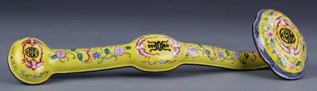 Chinese Enameled Bronze Ruyi Scepter: China, enameled bronze Ruyi scepter, yellow ground, highly decorative floral motifs throughout, with three black auspicious symbols, one at either end and the third in the middle. Length 14 in.
