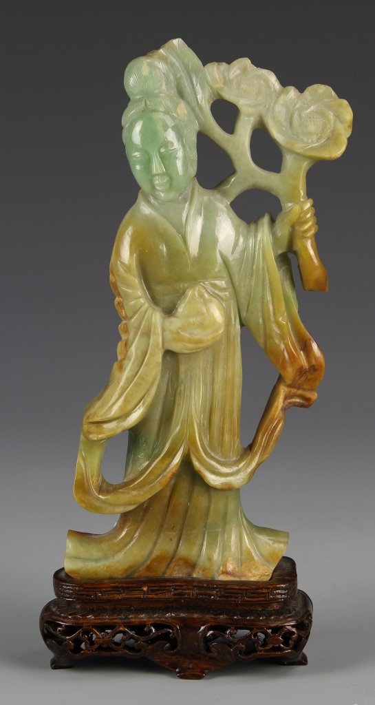 Chinese Jadeite Guanyin Figure: China, jadeite Guanyin, figure with a flowing robe holding a flowering branch, in a mottled green and yellow hue. Height 7 in., Width 3 in.
