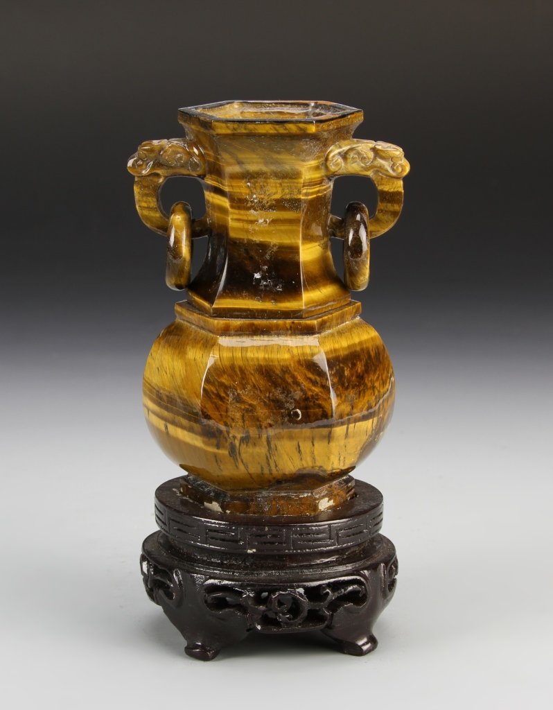Chinese Tiger-Eye Stone Vase with Base: China, tiger-eye stone vase, with six sides, two handles with connected rings, striations in the stone, and carved wood base. Height 14 in.