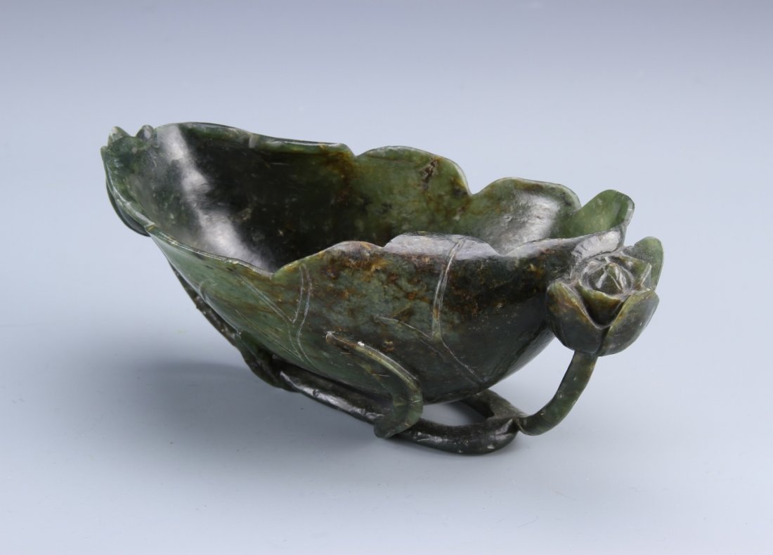 Chinese Jade Brush Washer: China, 19th C., jade brush washer, in ovular form of a turned up leaf, small floral detail attached to the side, deep green hue. Height 2 1/4 in., Width 7 in. Provenance: From the private collection o