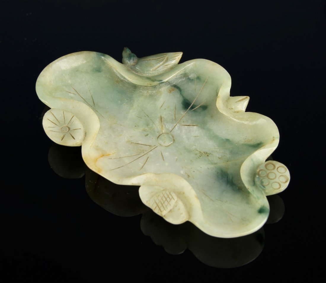 Chinese Jadeite Brush Washer: China, jadeite brush washer, in organic form, with scalloped edges, floral motifs, carved linear details, and striations in the stone. Height 3 in., Length 4 1/2 in.