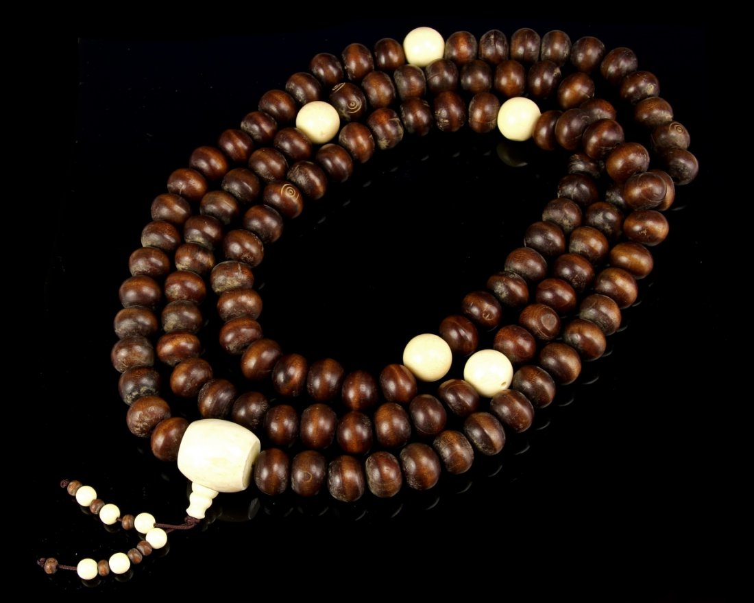 Chinese Wood Buddhist Prayer Beads: China, wood Buddhist prayer beads, comprising of 108 round wood beads carved as puti seeds, interspersed with 5 round ivory beads and central ivory piece. Length 66 in.
