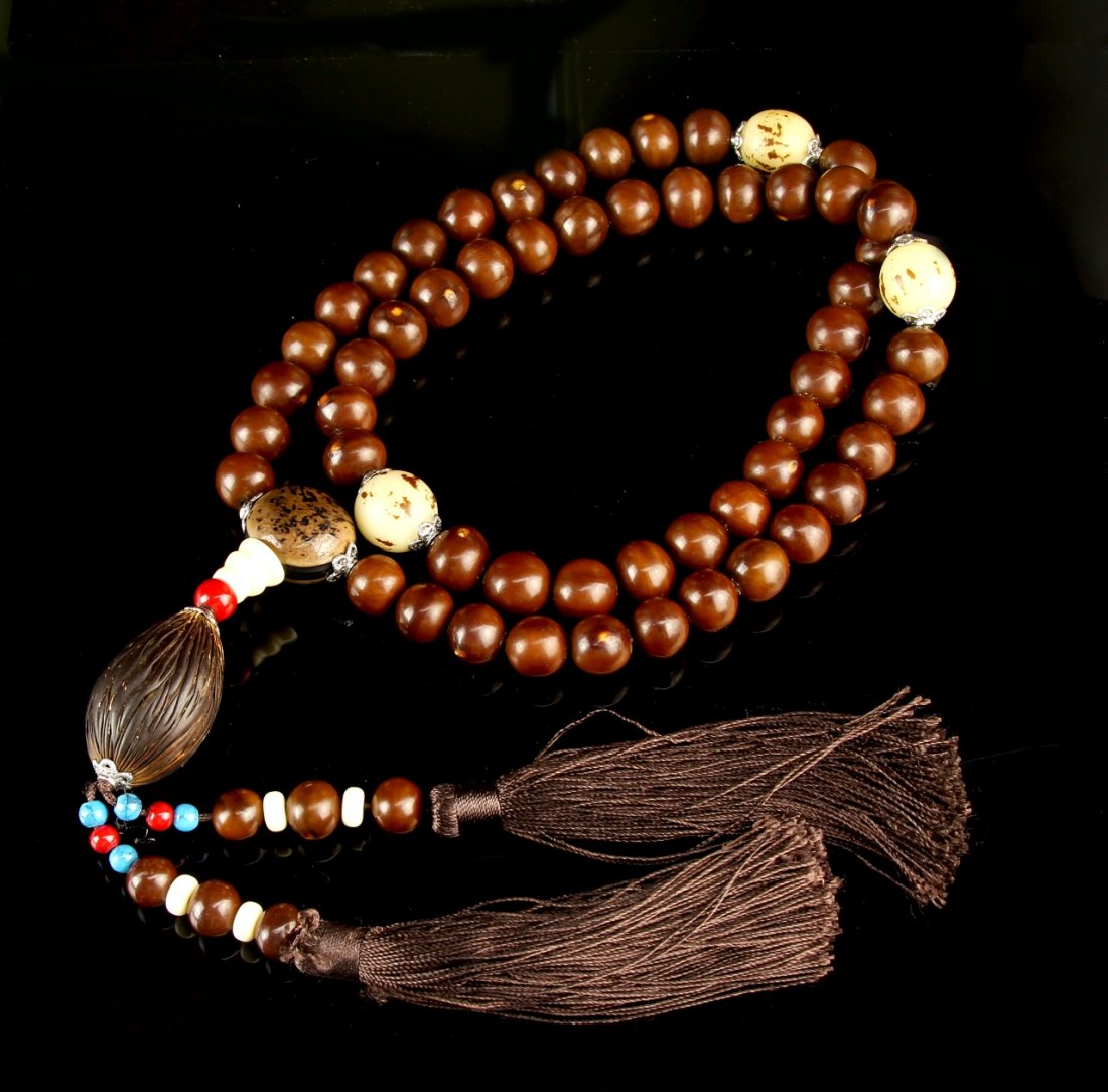 Chinese Puti Beaded Necklace: China, puti beaded necklace, with spherical and oblong beads, blue and red accent beads, and matching brown hued tassels. Length 44 in.