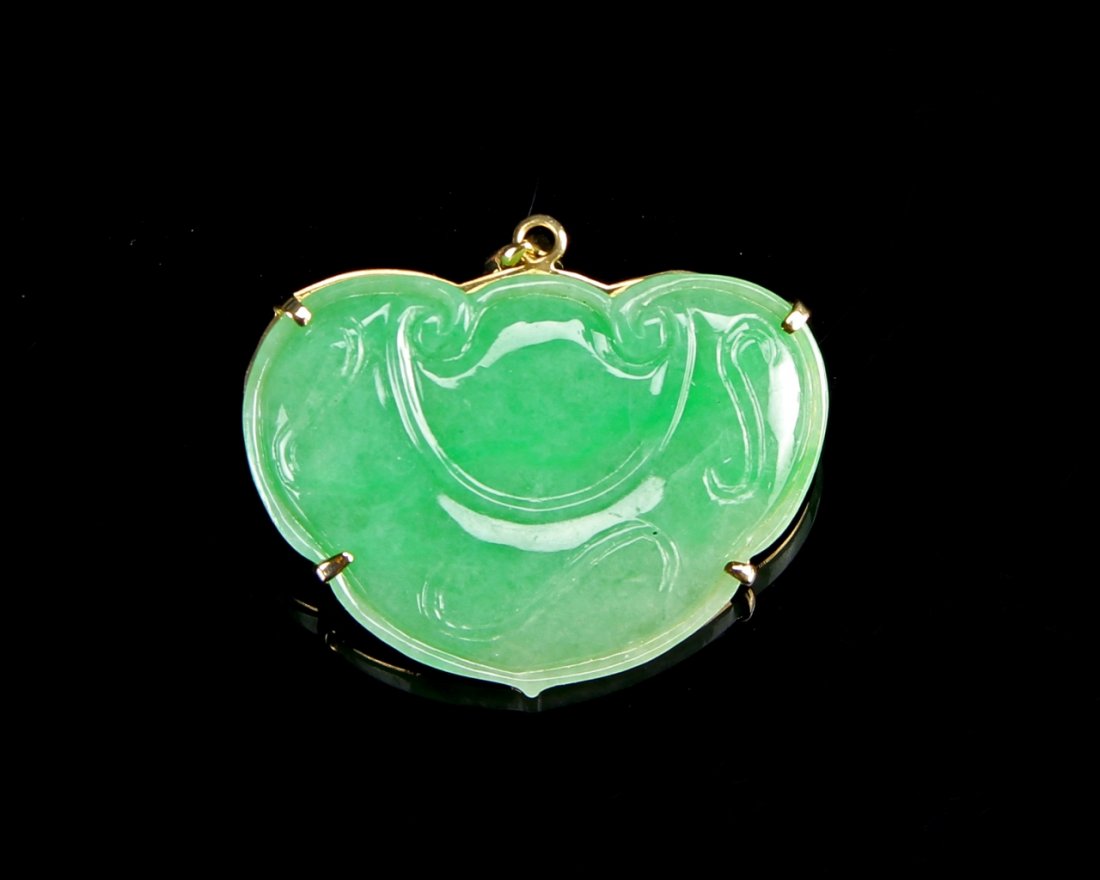 Chinese Jadeite and 14 K Gold Pendant: China, jadeite and 14 K gold pendant, rounded shape with delicate curving lines in carved relief, held in gold rim backing with upper chain loop. Height 1 1/4 in.