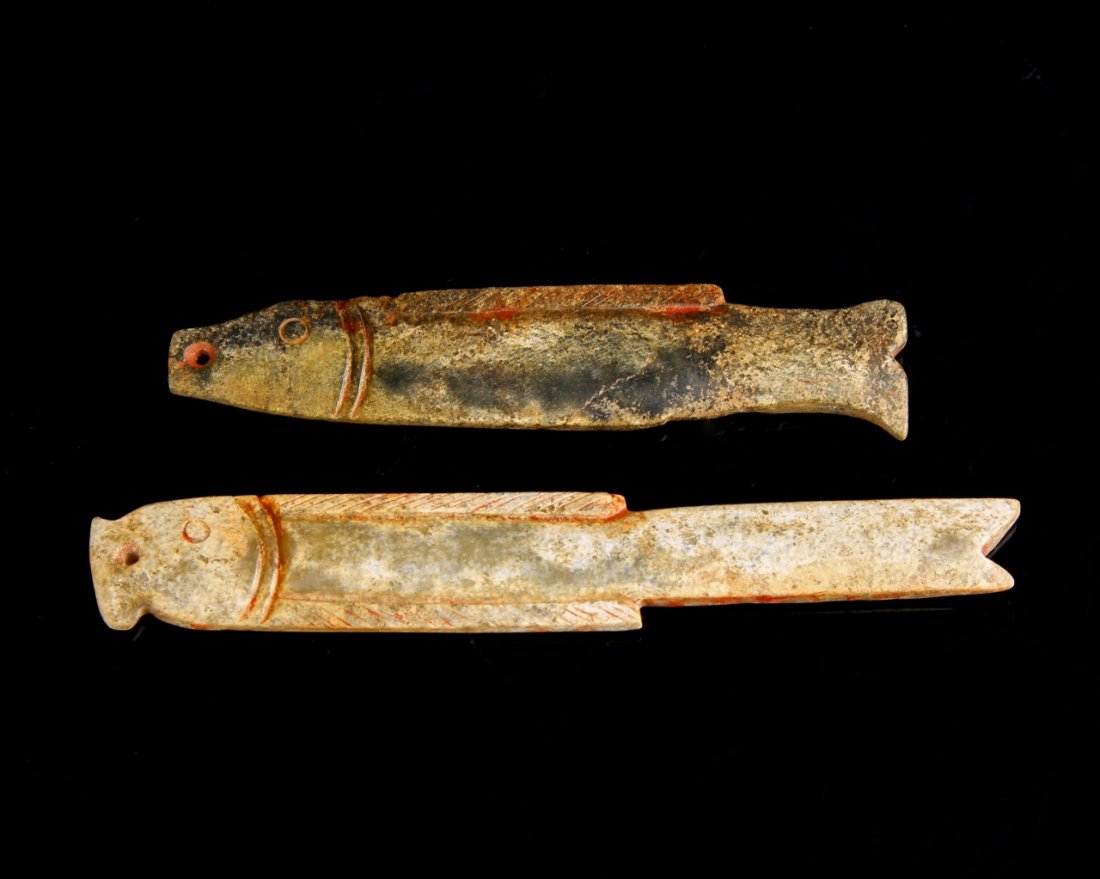 Two Chinese Jade Fish: China, Shang Period, two jade fish, simplistically carved, with simple lines, in a mottled brown hue, with striations in the stone. Length 3 3/4 in.