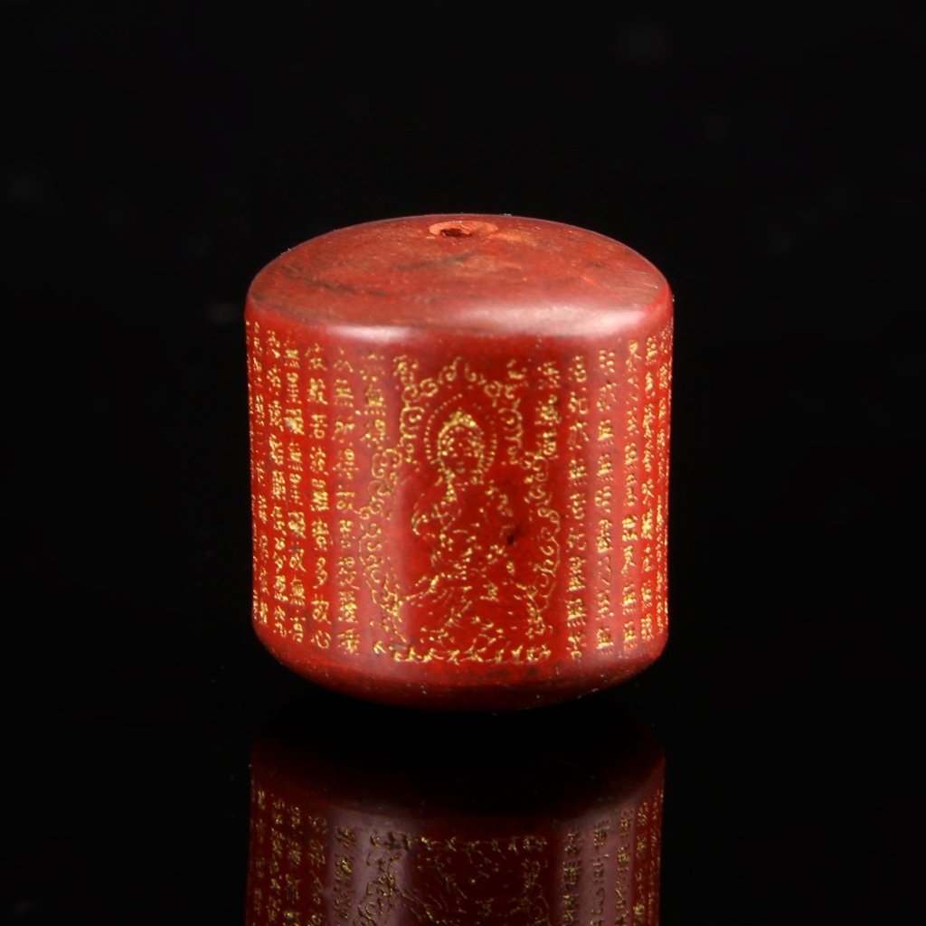 Chinese Carved Zhusha Prayer Bead: China, 19th C., carved Zhusha prayer bead in a red hue, with gilt Buddhist inscriptions and a small seated gilt Buddha figure. Height 20.47 mm, Width 18.21 mm.