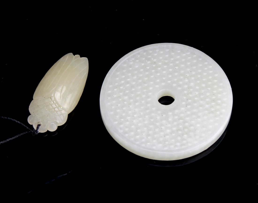 Two Chinese Jade Pendants: China, two jade pendants, one in the form of a locust smoothly carved to show the head and wings of the bug, the other in the form of a Pi, with a dotted design on the face carved in relief, both in a