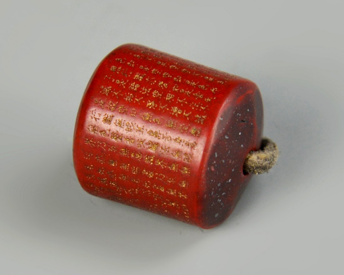 Chinese Red Stone Bead: China, 19th C., red stone bead, in cylindrical form, in a deep red hue, with Buddhist inscriptions. Length 1/2 in., Width 1/2 in.