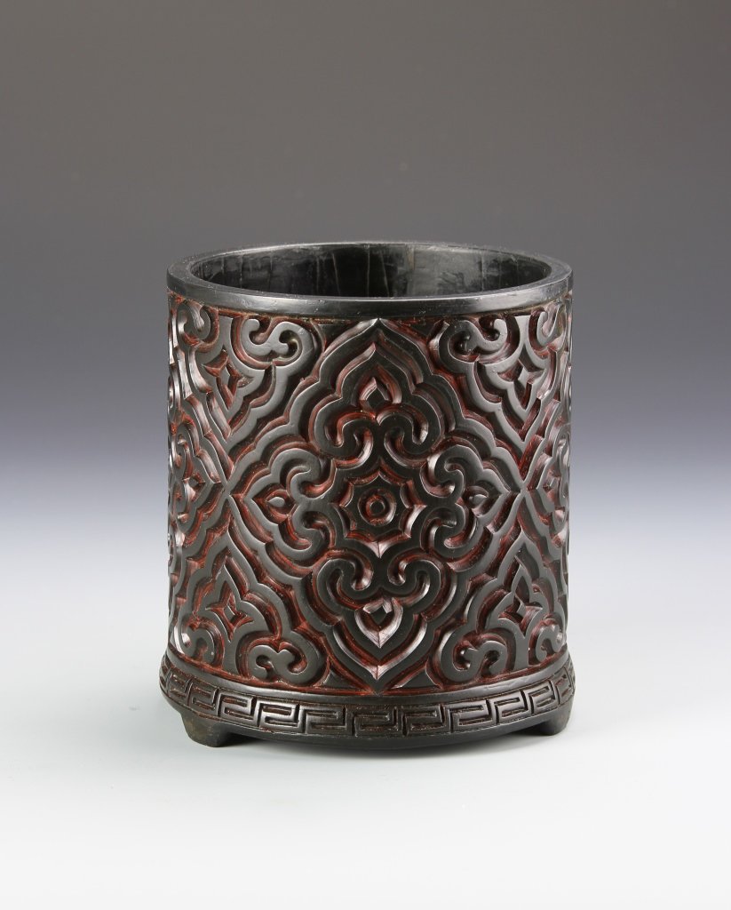Chinese Lacquer Brush Pot: China, lacquer brush pot, intricately carved in a decorative design with patterned border and calligraphy marking on the base. Height 5 3/8 in., Diameter 5 in.