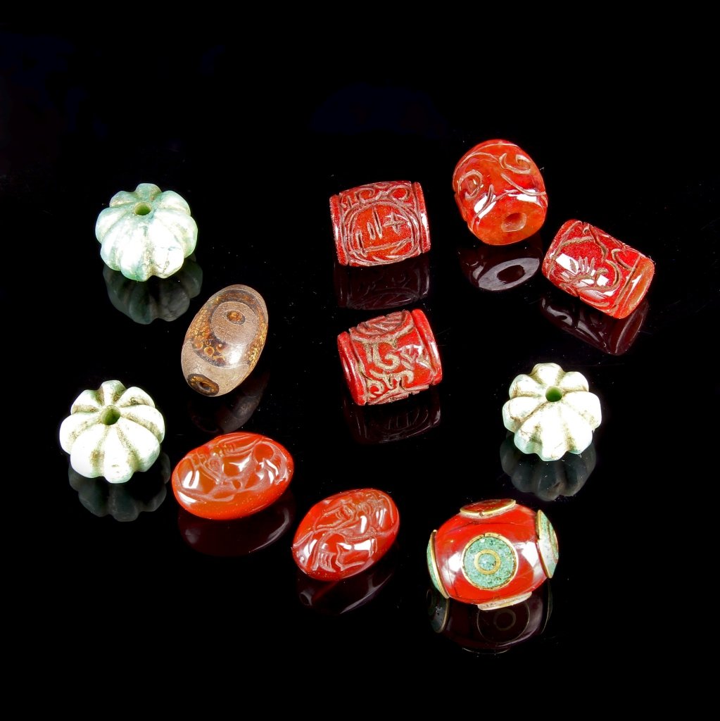 Eleven Chinese Tibetan Antique Prayer Beads: China, eleven Tibetan antique prayer beads, including six red colored beads with carved decoration, three floriform light green beads, and one brown bead. Length 1 in.