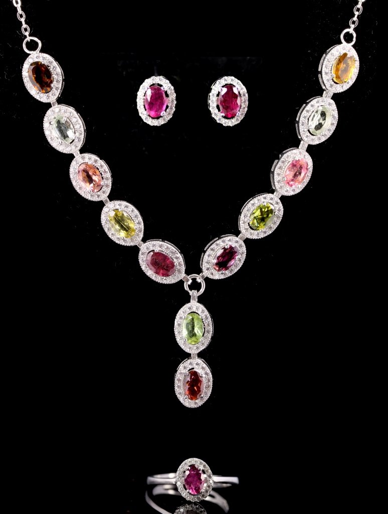 Set of Chinese Necklace, Ring, and Earrings: China, set of tourmaline and silver necklace, ring and earrings, with centrally set tourmaline of different shades surrounded by smaller gemstones. Weight 13.32 g.