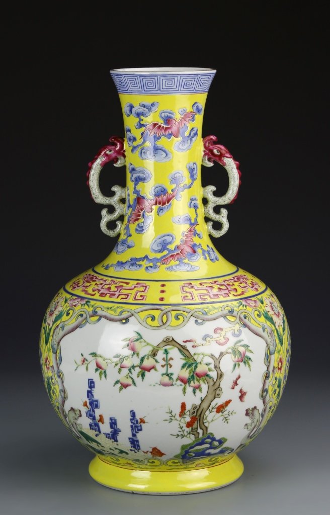Chinese Famille Rose Vase: China, bright yellow colored Famille Rose footed vase, with dragon-shaped ears and a variety of auspicious symbols including bats, dragons, peaches, and fish. Height 15 3/4 in.