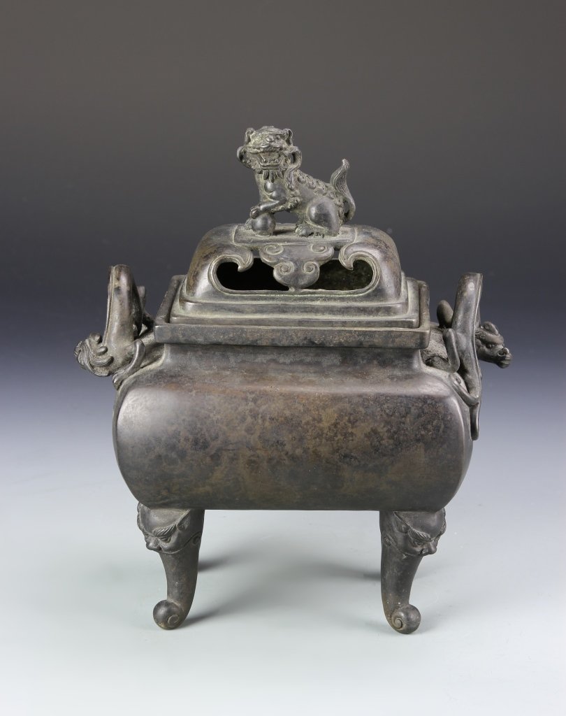 Chinese Bronze Censer: China, bronze censer with a foo lion sitting on top of the cover, two dragon shaped handles on both sides, with animal masks on each of the four legs, four character mark on base. Height 10 in.